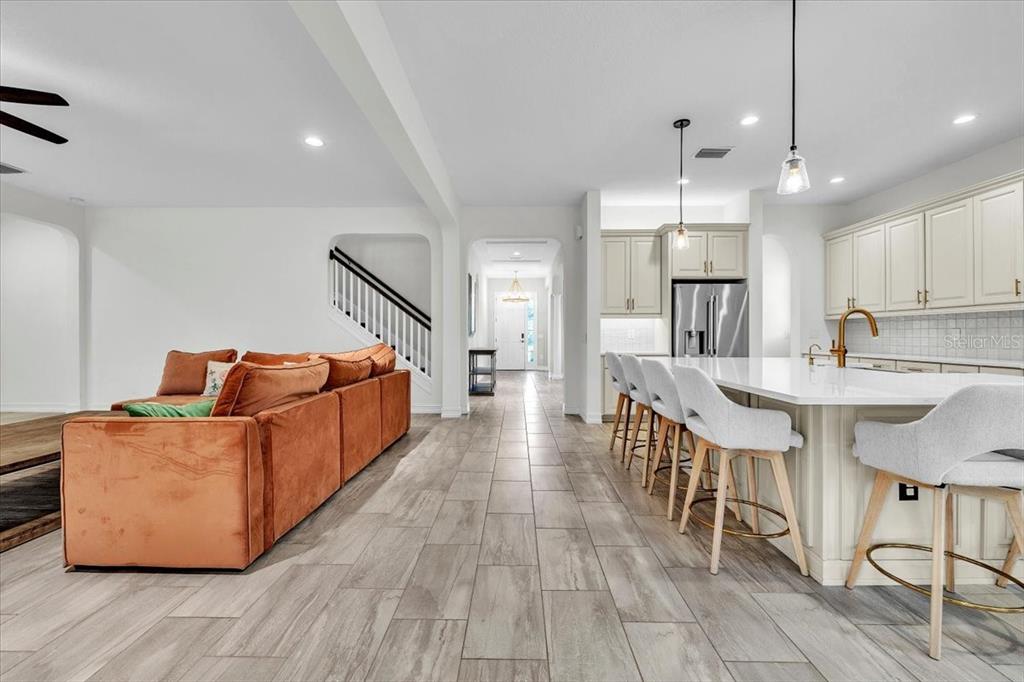 An open-concept living room and kitchen featuring a large orange sofa and white island seating — 17923 BARN CLOSE DRIVE, LUTZ, FL