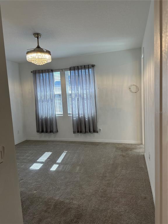A carpeted bedroom features a crystal chandelier ceiling fan and two windows with gray curtains — 1862 ISLAND VILLAGE WAY, CELEBRATION, FL