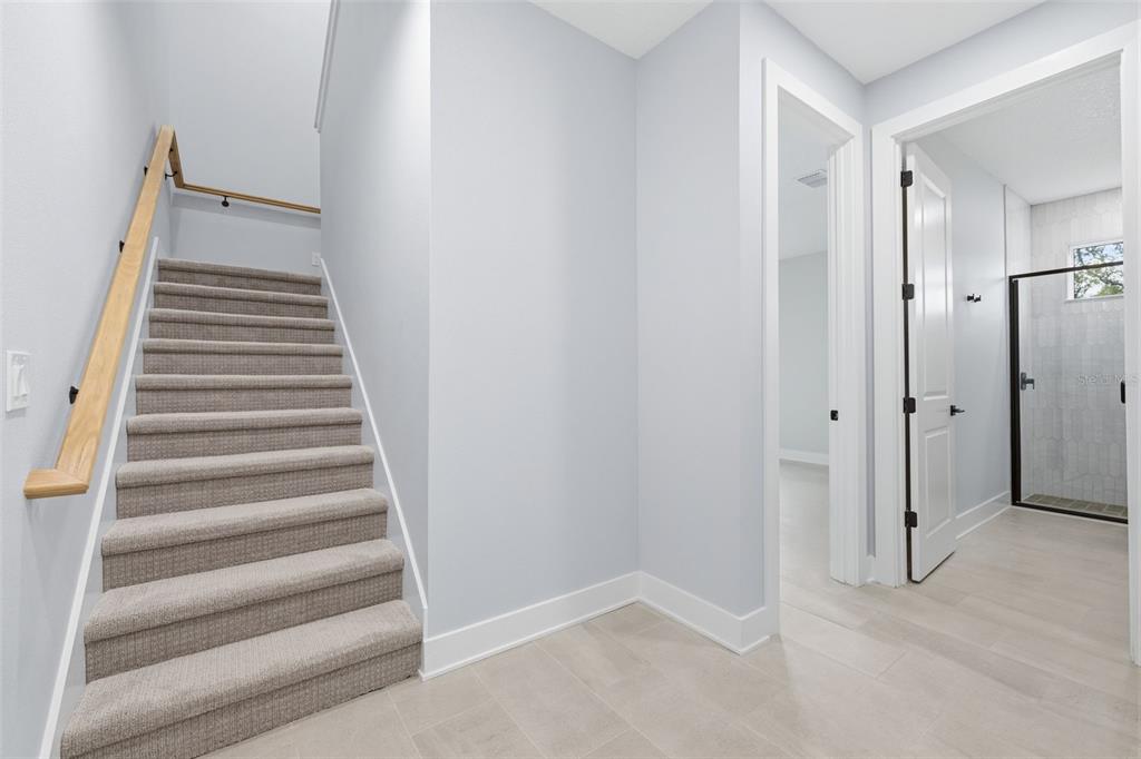 A staircase with carpeted steps and a wooden handrail sits beside a tiled hallway — 4208 W CARMEN STREET UNIT D, TAMPA, FL