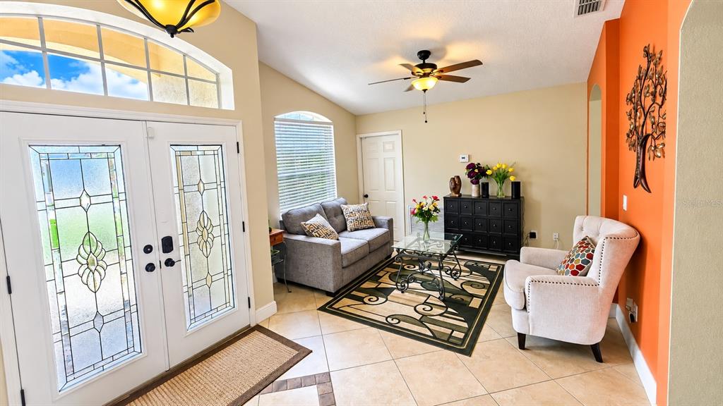 A tan stucco house with a stone-accented garage, red double front doors, and palm landscaping — 148 BELFRY DRIVE, DAVENPORT, FL