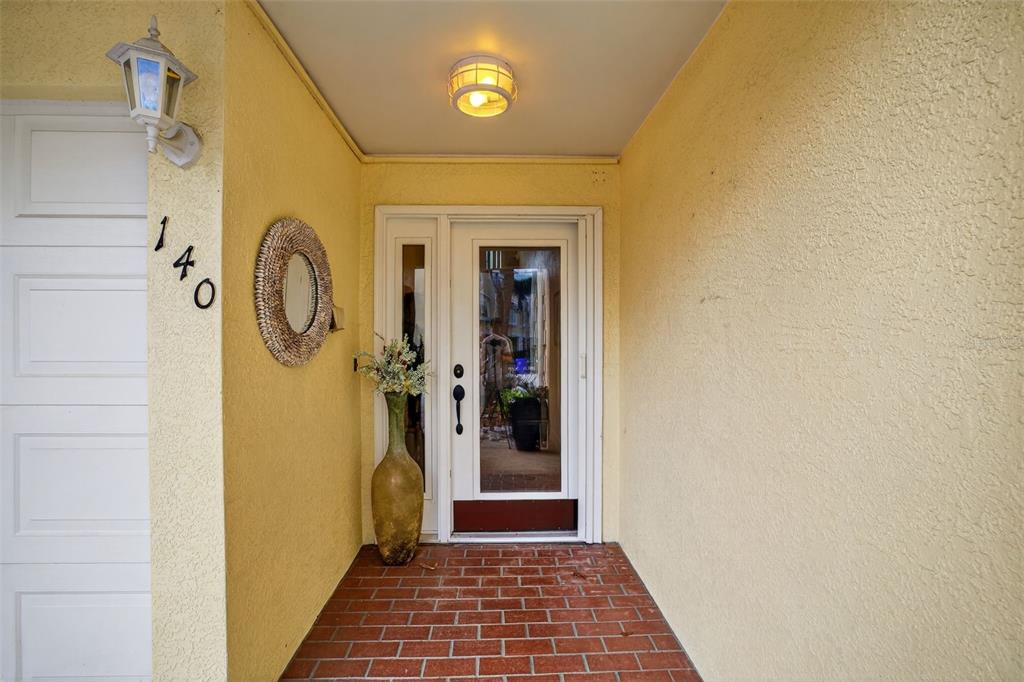 A front entryway features a brick floor, a white door with glass, and yellow walls — 140 BRENT CIRCLE, OLDSMAR, FL