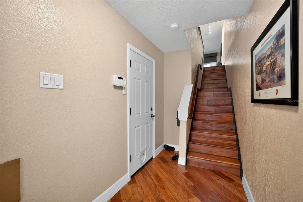 An entryway features hardwood flooring, a white door, and a wooden staircase leading upstairs — 140 BRENT CIRCLE, OLDSMAR, FL