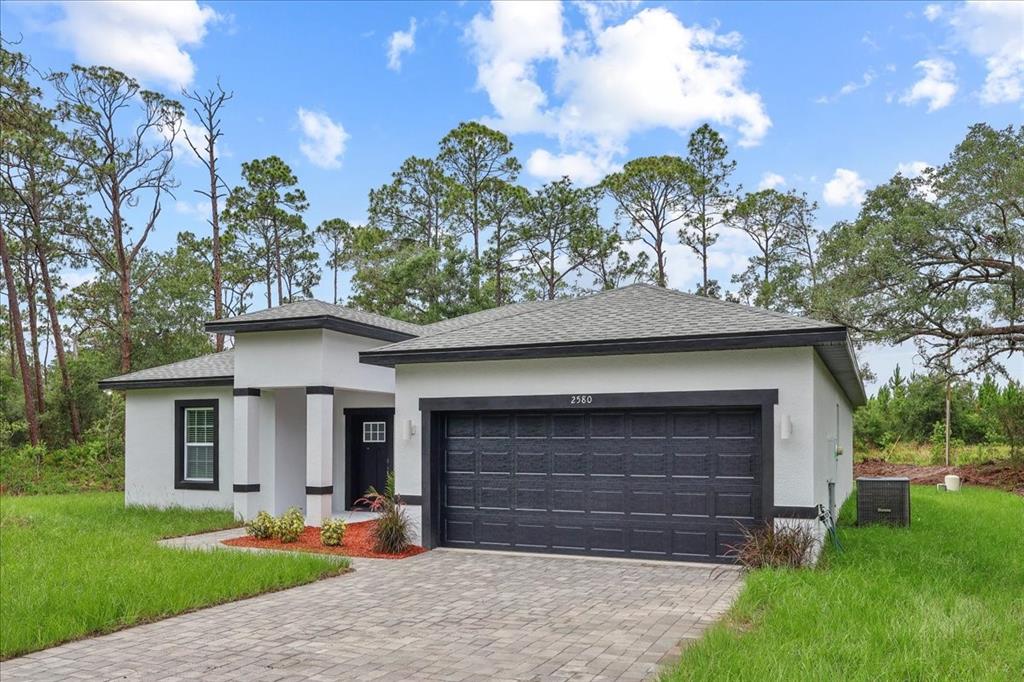 A single-story house with a white stucco exterior, black trim, and a two-car garage — 2580 PLUMOSA DRIVE, INDIAN LAKE ESTATES, FL