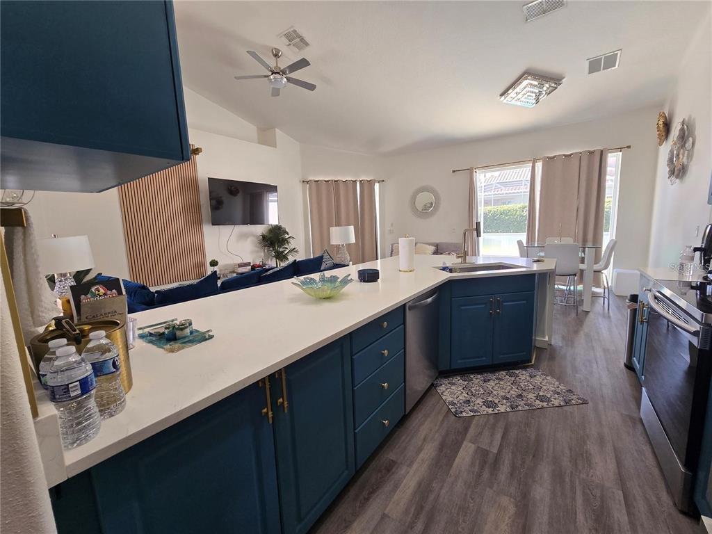 A kitchen with blue cabinets and white countertops opens into a living and dining area — 751 BRUNELLO DRIVE, DAVENPORT, FL