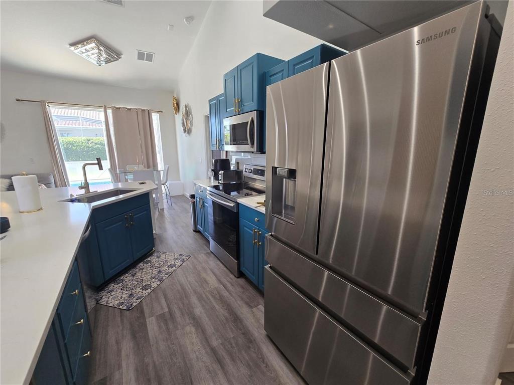 A kitchen features blue cabinets, stainless steel appliances, and a white countertop island — 751 BRUNELLO DRIVE, DAVENPORT, FL