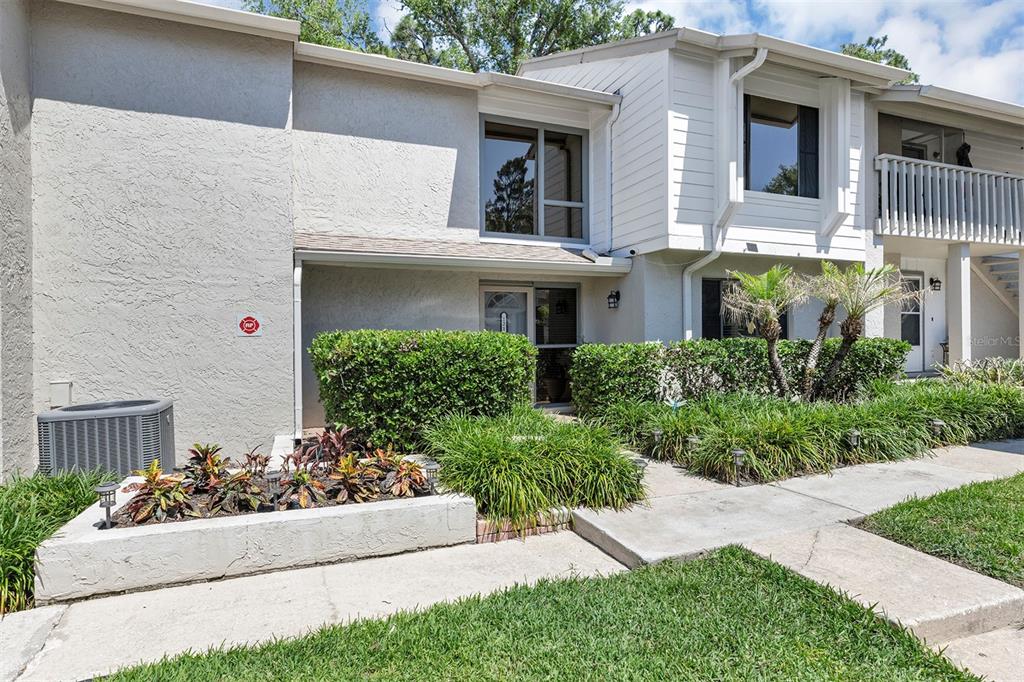 A two-story townhouse exterior with a concrete walkway, landscaping, and a small front patio — 121 CROWN POINT CIRCLE UNIT 121, LONGWOOD, FL