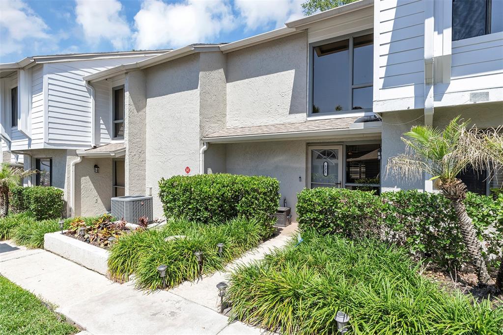 A two-story townhouse exterior features light-colored stucco, white siding, and a landscaped front walkway — 121 CROWN POINT CIRCLE UNIT 121, LONGWOOD, FL