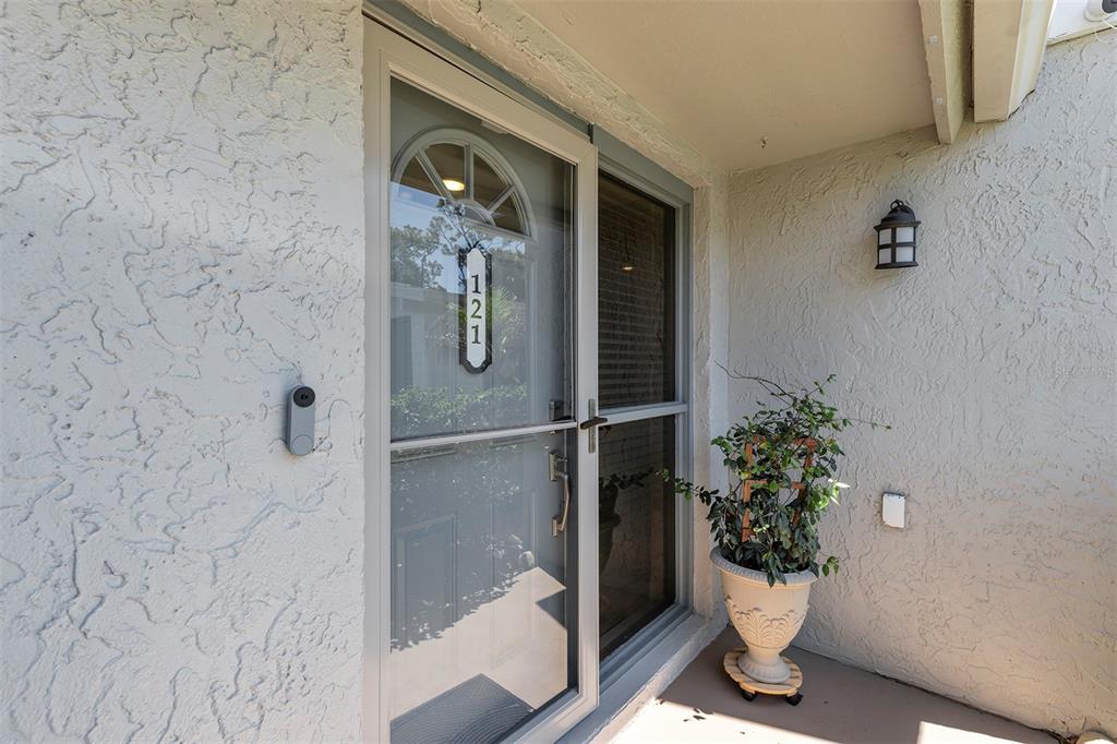 A front entryway features a glass storm door, a house number plaque, and a potted plant — 121 CROWN POINT CIRCLE UNIT 121, LONGWOOD, FL