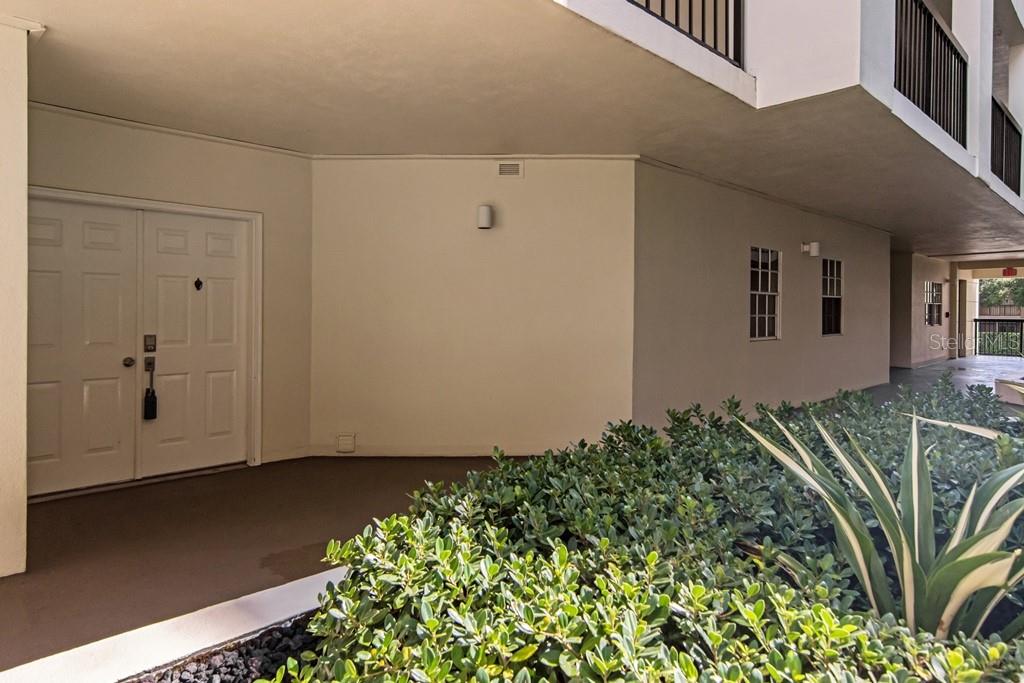A beige exterior wall features a double-door entrance and a small garden bed — 1002 S HARBOUR ISLAND BOULEVARD UNIT 1101, TAMPA, FL