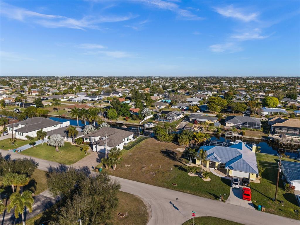 An aerial view shows a vacant residential lot situated between houses along a canal — 241 SW 40TH STREET, CAPE CORAL, FL