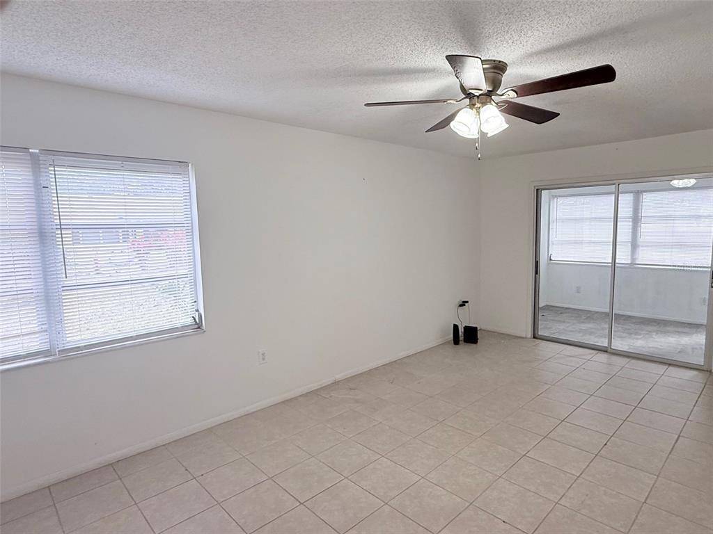An empty room with white walls, tile flooring, a ceiling fan, and sliding glass doors — 390 301 BOULEVARD W UNIT 8D, BRADENTON, FL