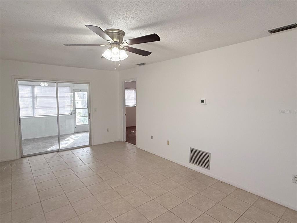 A room with tile flooring, a ceiling fan, and sliding glass doors leading to a porch — 390 301 BOULEVARD W UNIT 8D, BRADENTON, FL