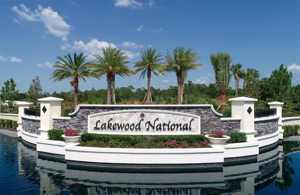 A stone monument sign for Lakewood National stands in front of palm trees and water — 5624 PALMER CIRCLE UNIT 105, BRADENTON, FL
