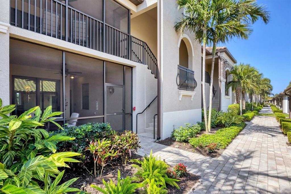 An exterior view of a multi-story apartment building with a screened-in patio and walkway — 5624 PALMER CIRCLE UNIT 105, BRADENTON, FL