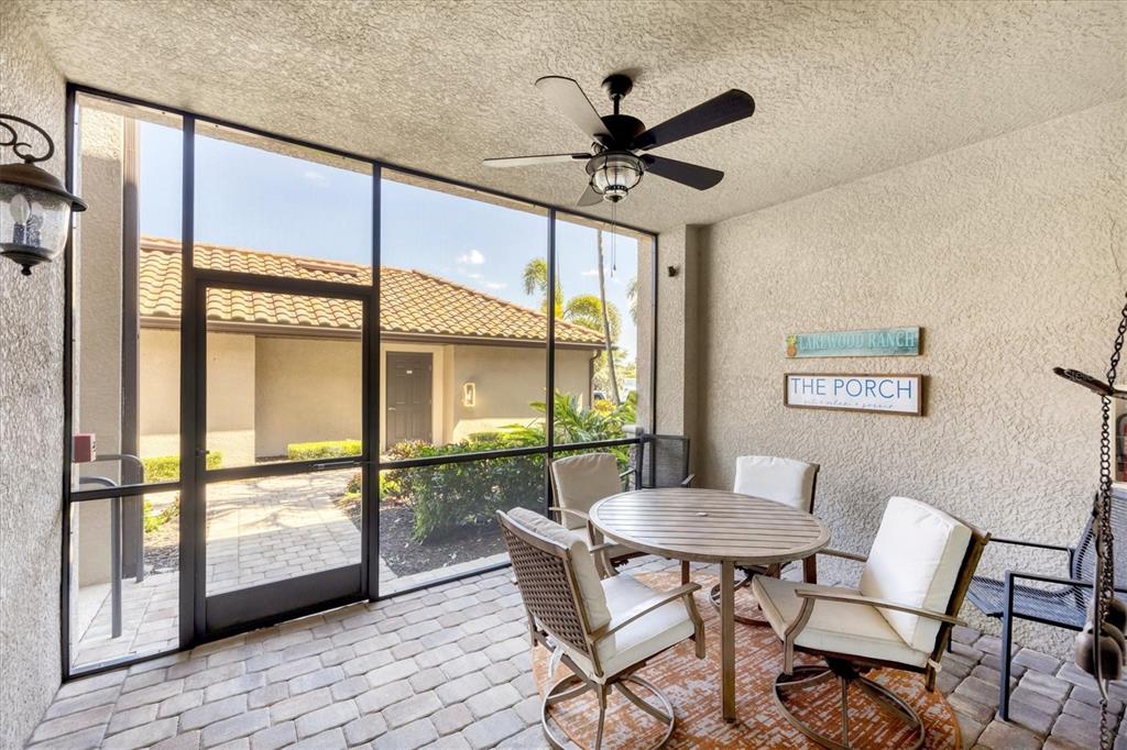 A screened-in patio features a dining set, ceiling fan, and a view of a neighboring building — 5624 PALMER CIRCLE UNIT 105, BRADENTON, FL