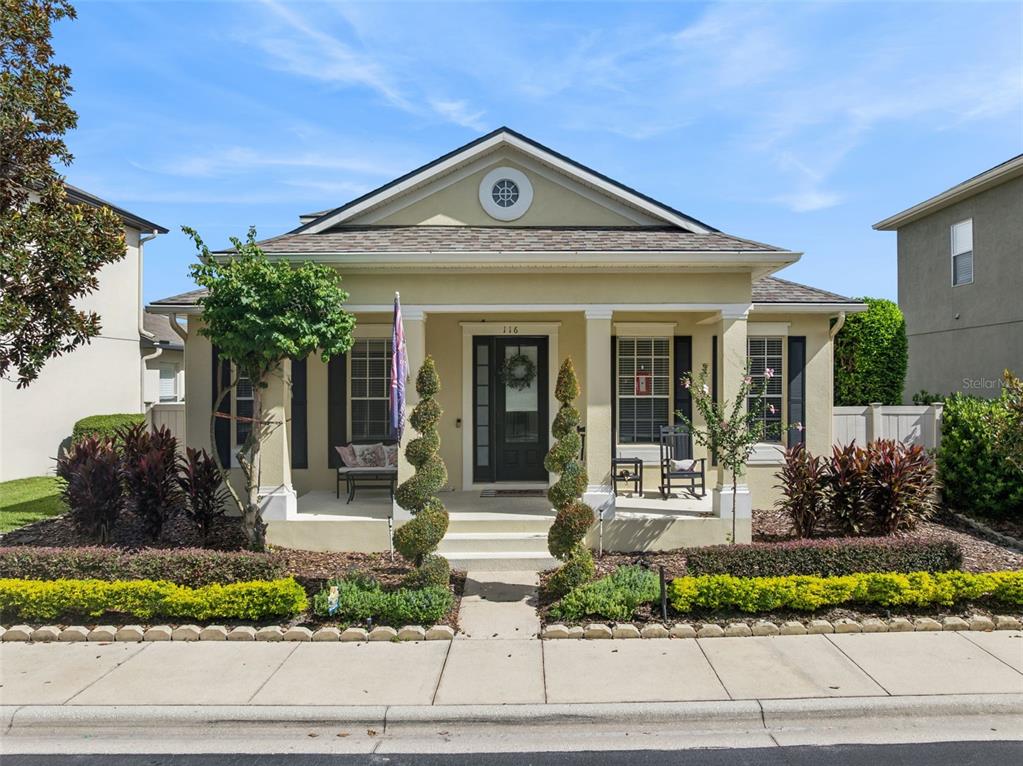 A single-story house with a covered front porch, spiral topiaries, and a yellow exterior — 116 AVERY LAKE DRIVE, WINTER SPRINGS, FL