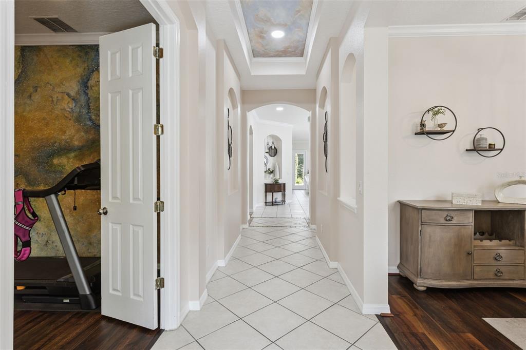 A hallway with tiled floors, a tray ceiling, and an open door revealing a treadmill — 116 AVERY LAKE DRIVE, WINTER SPRINGS, FL