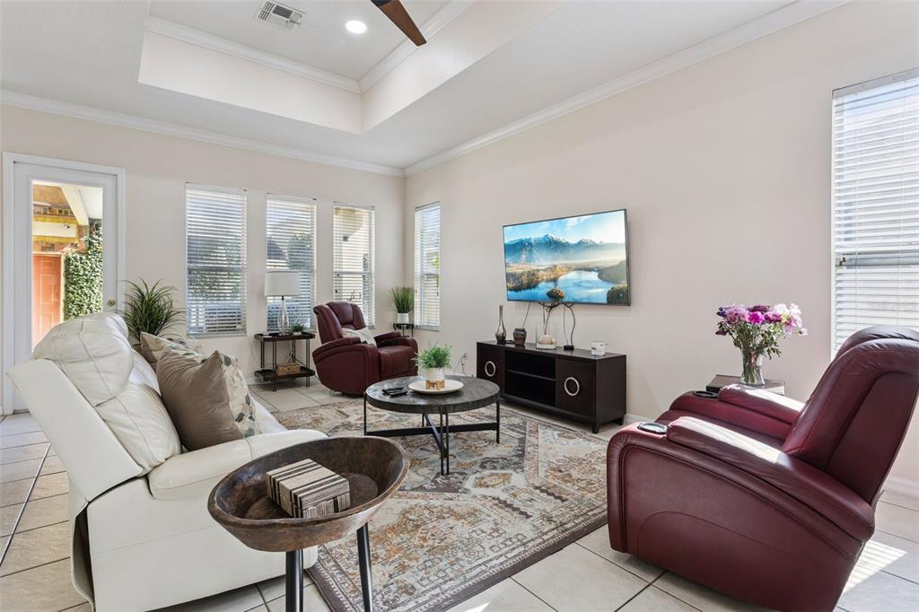 A living room features a tray ceiling, tile floors, a rug, and leather recliners — 116 AVERY LAKE DRIVE, WINTER SPRINGS, FL