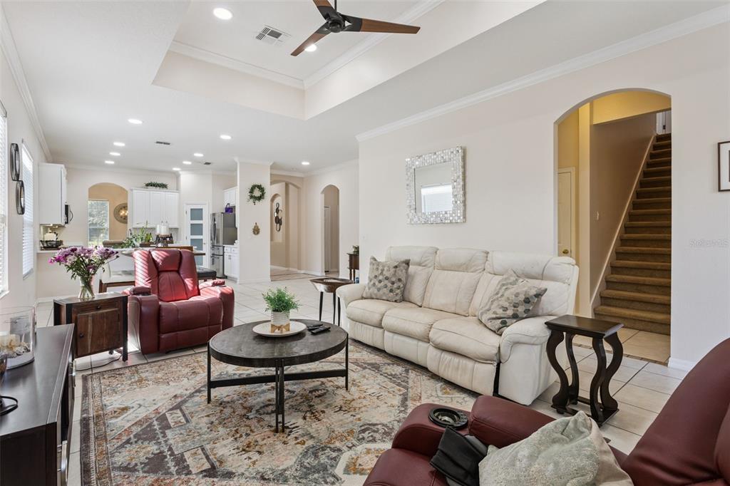 A living room with a white sofa, red recliners, a round coffee table, and a staircase — 116 AVERY LAKE DRIVE, WINTER SPRINGS, FL