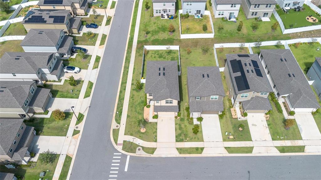 An aerial view shows several suburban houses with driveways and lawns along a paved street — 2207 BEAR PEAK ROAD, MINNEOLA, FL