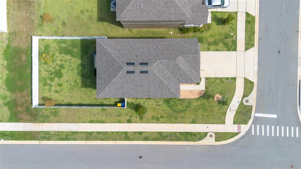 An aerial view shows a single-story house with a gray roof and a fenced backyard — 2207 BEAR PEAK ROAD, MINNEOLA, FL