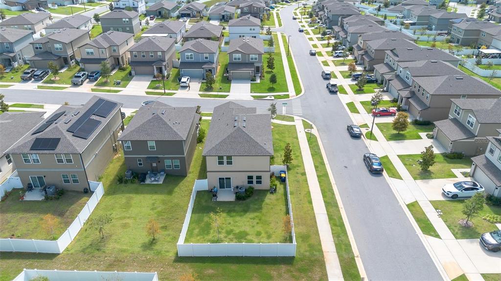 An aerial view shows suburban houses with fenced backyards and streets with parked cars — 2207 BEAR PEAK ROAD, MINNEOLA, FL