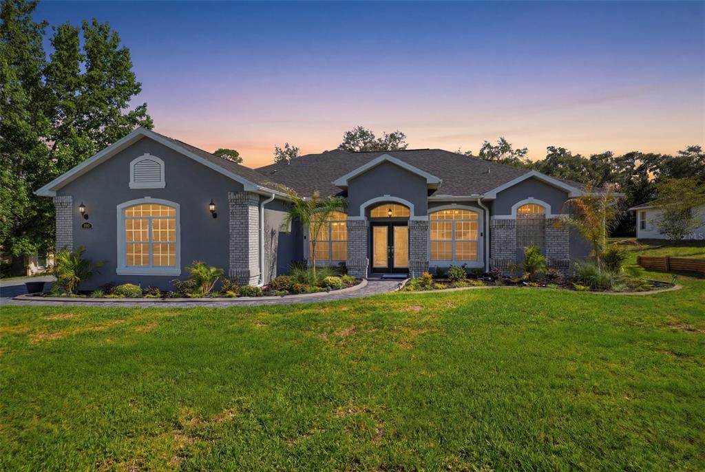 A gray single-story house with a brick-accented facade and a curved stone walkway — 12041 SAPPHIRE DRIVE, SPRING HILL, FL