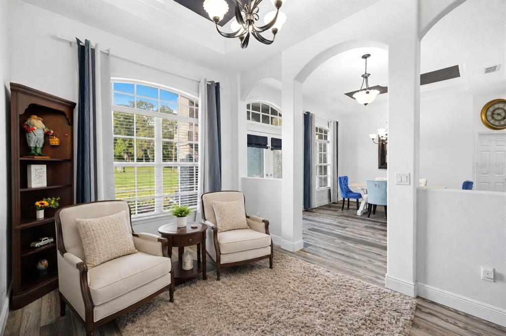 A sitting area with two armchairs and a bookshelf opens into a dining room — 12041 SAPPHIRE DRIVE, SPRING HILL, FL