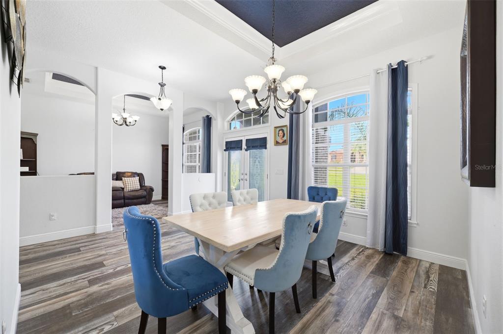 A dining room features a wooden table, blue and white chairs, and a dark ceiling — 12041 SAPPHIRE DRIVE, SPRING HILL, FL