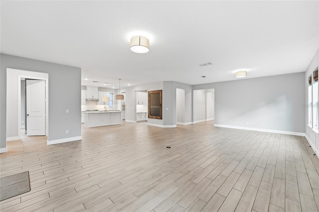 An open-concept living area features light wood-look tile flooring, gray walls, and a white kitchen — 8236 PROCIDA ISLE LANE, WINDERMERE, FL