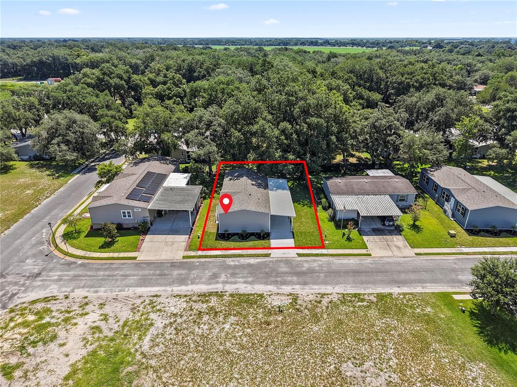 An aerial view shows a single-story house with a carport outlined in red — 25136 HUCKLEBERRY WAY, ASTATULA, FL