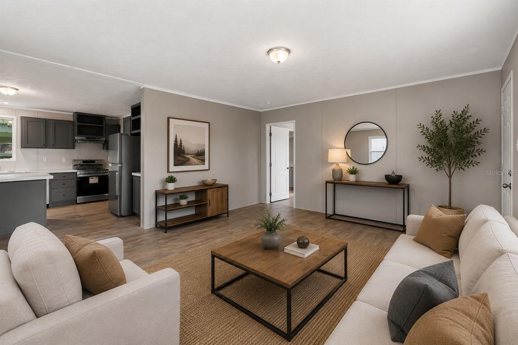 A living room with light-colored sofas, a wooden coffee table, and an open-concept kitchen — 25136 HUCKLEBERRY WAY, ASTATULA, FL