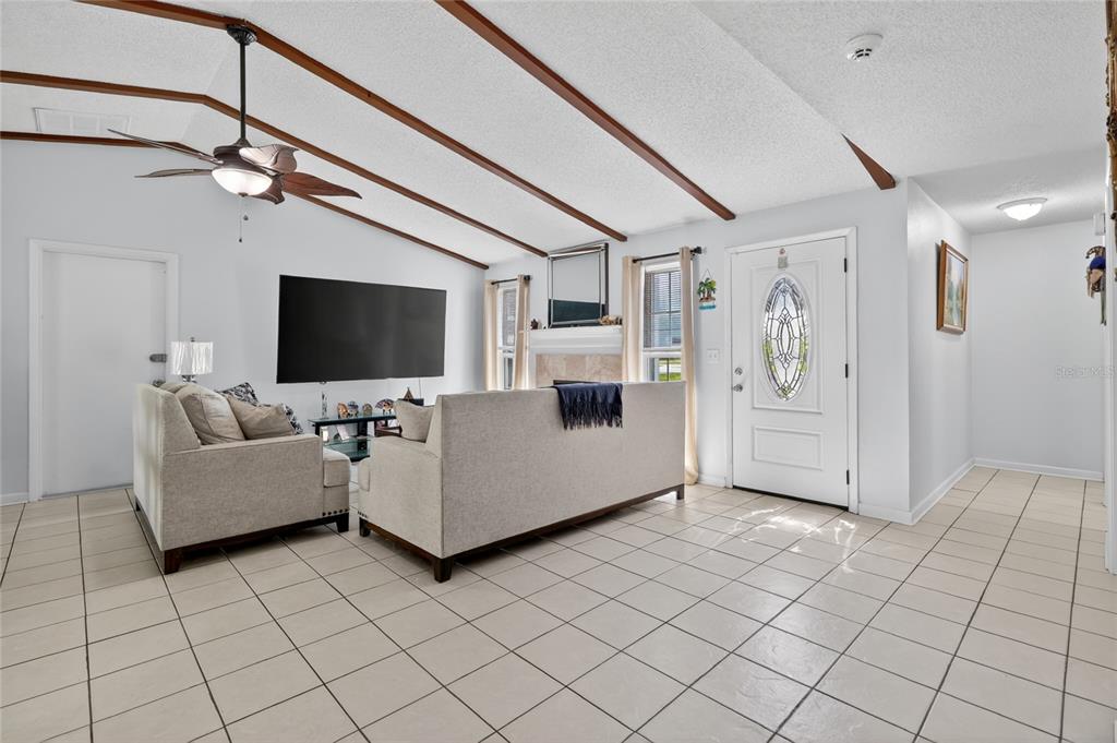 A living room features a vaulted ceiling with exposed beams, tile flooring, and a fireplace — 4646 OLD 37 ROAD, LAKELAND, FL