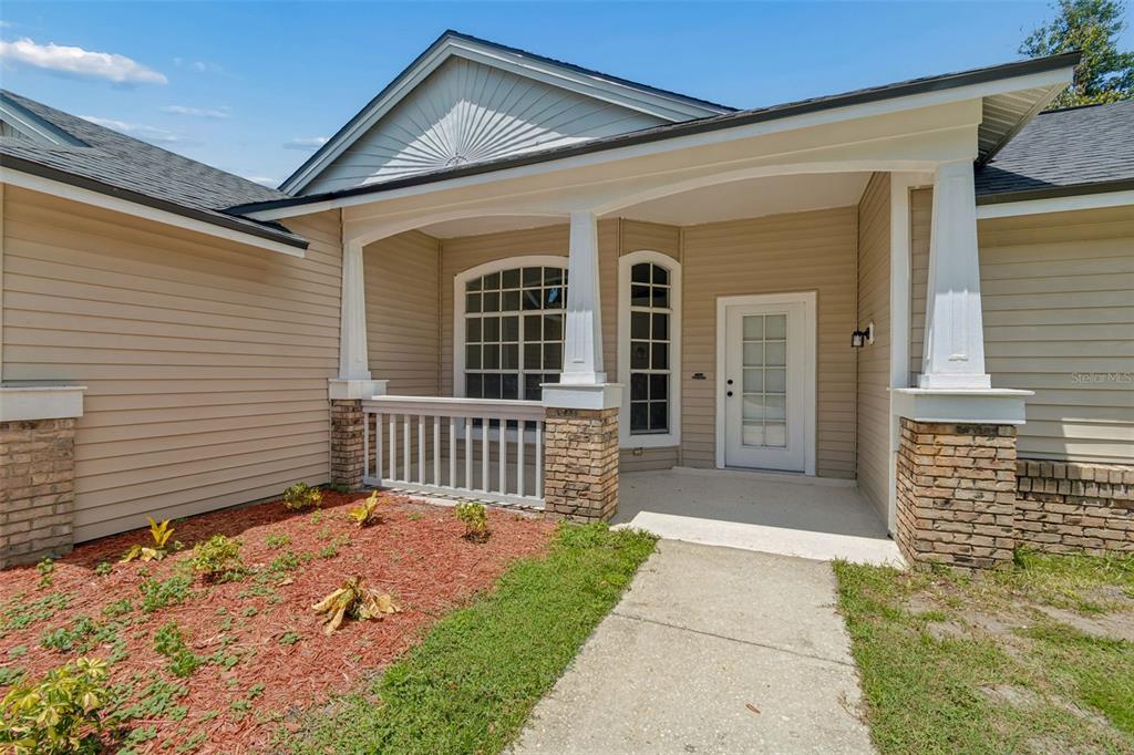 The exterior of a house features a covered porch with stone columns and a white door — 3315 SILVERPOND DRIVE, PLANT CITY, FL