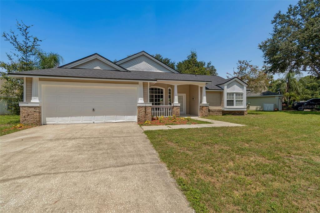A single-story house with a beige exterior, a two-car garage, and a covered front porch — 3315 SILVERPOND DRIVE, PLANT CITY, FL