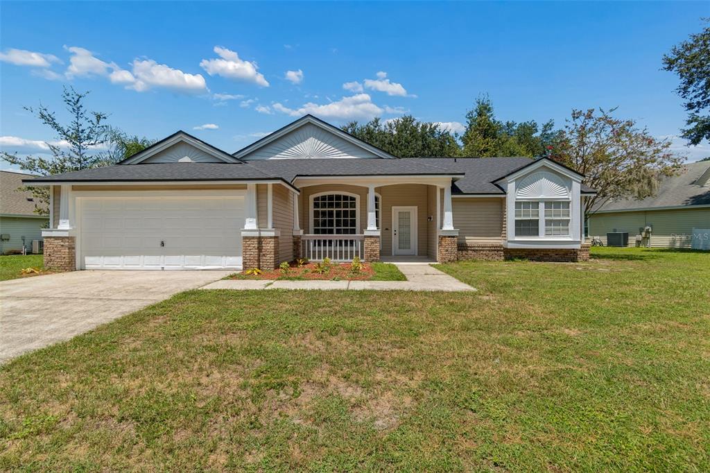 A single-story house with a beige exterior, brick accents, a two-car garage, and a front porch — 3315 SILVERPOND DRIVE, PLANT CITY, FL