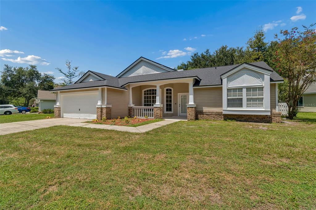 A single-story house with tan siding, a two-car garage, and a covered front porch — 3315 SILVERPOND DRIVE, PLANT CITY, FL