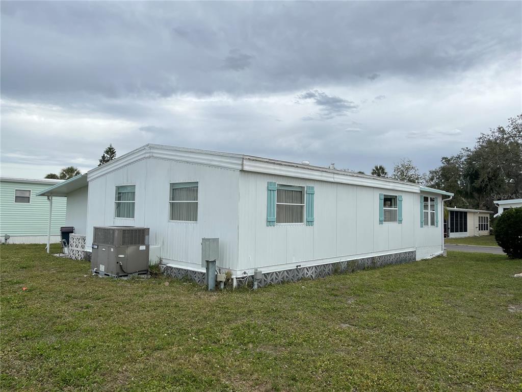 A white mobile home with light blue shutters sits on a grassy lot — 626 CERVINA DRIVE, VENICE, FL