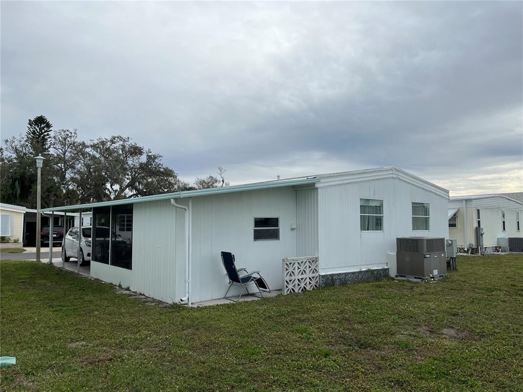 The exterior of a white mobile home features a screened-in porch and a central air unit — 626 CERVINA DRIVE, VENICE, FL