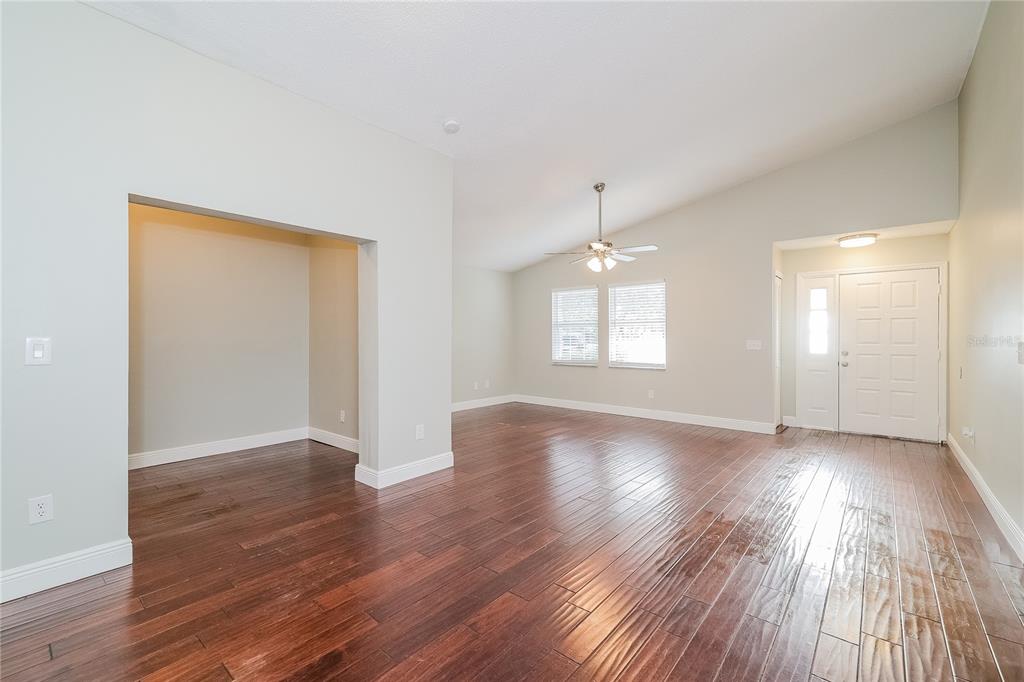 An empty living room features dark wood flooring, a vaulted ceiling, and a front entryway — 1535 LAWNDALE CIRCLE, WINTER PARK, FL