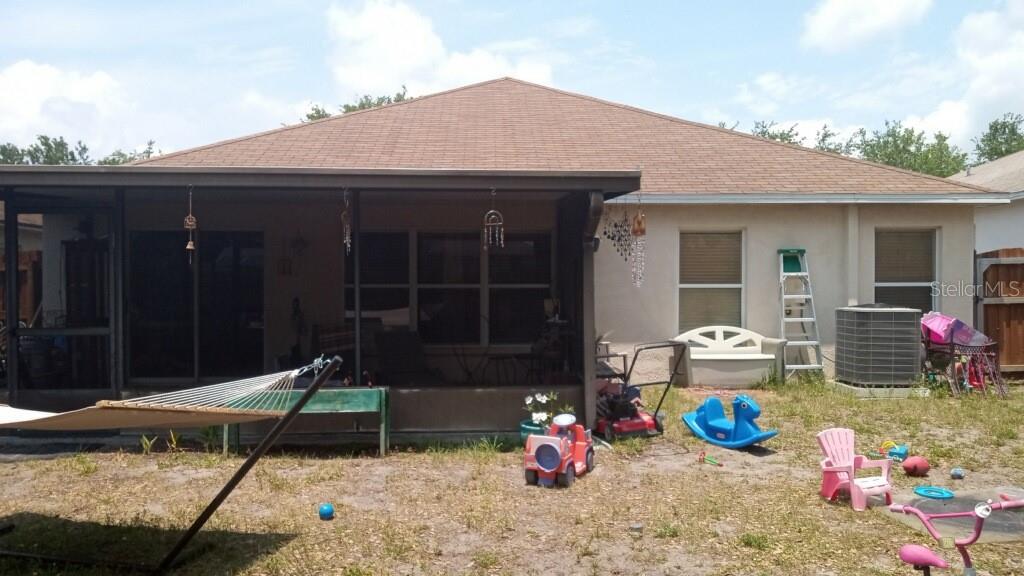 The exterior view shows a house with a screened-in patio and a grassy backyard — 10933 SUBTLE TRAIL DRIVE, RIVERVIEW, FL