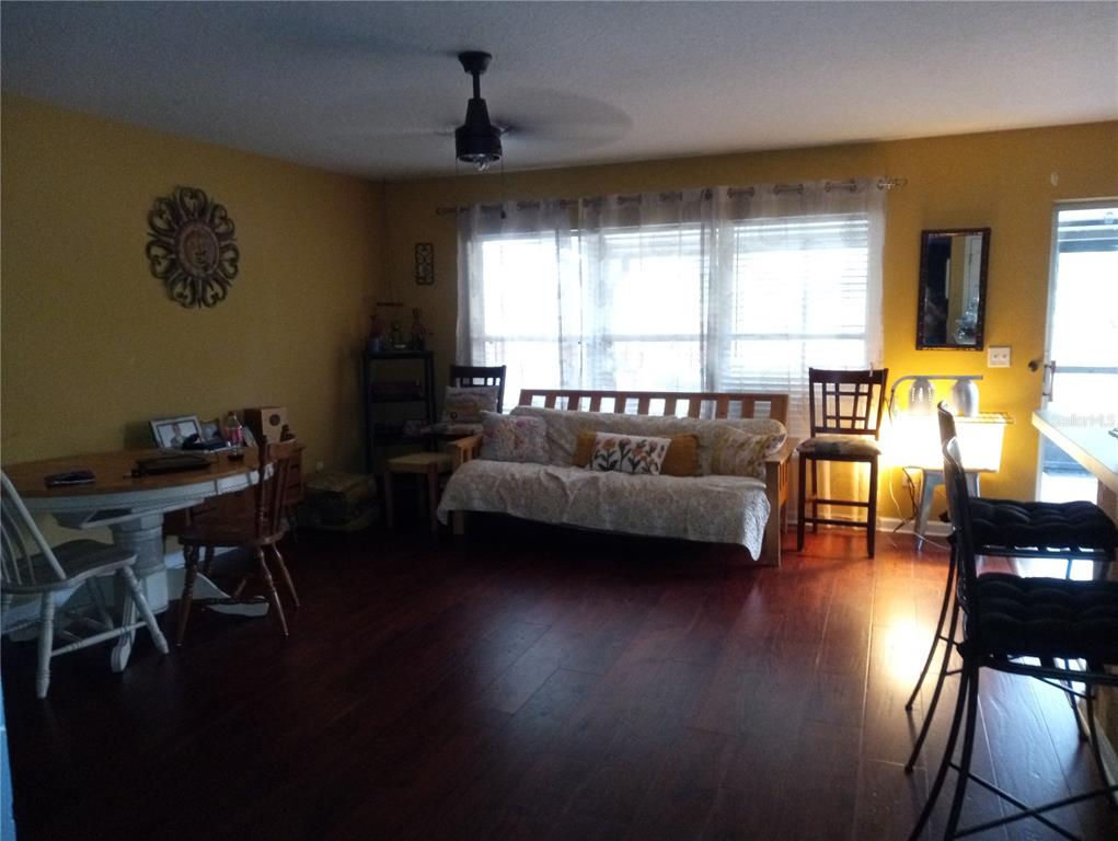 A living and dining area features dark wood floors, yellow walls, and a wooden futon — 10933 SUBTLE TRAIL DRIVE, RIVERVIEW, FL