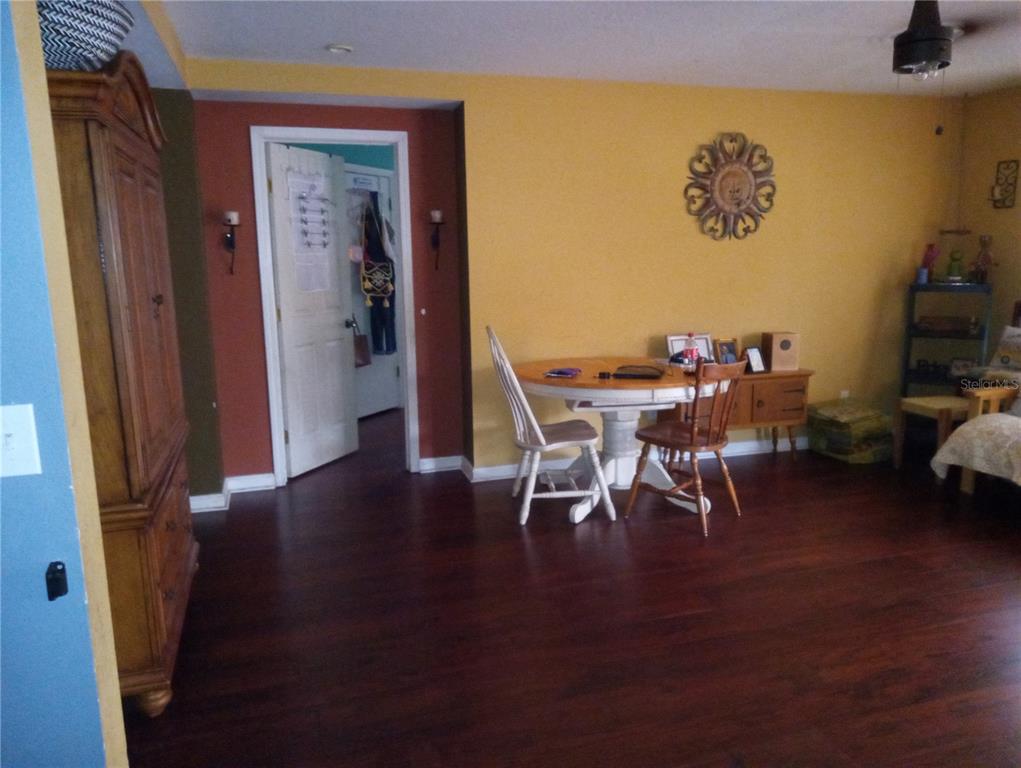 A dining area with a round table, two chairs, and dark wood flooring — 10933 SUBTLE TRAIL DRIVE, RIVERVIEW, FL