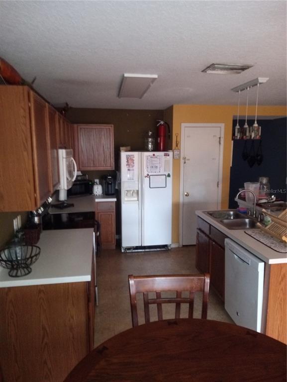 A kitchen with wood cabinets, white appliances, a central island, and a dining table — 10933 SUBTLE TRAIL DRIVE, RIVERVIEW, FL