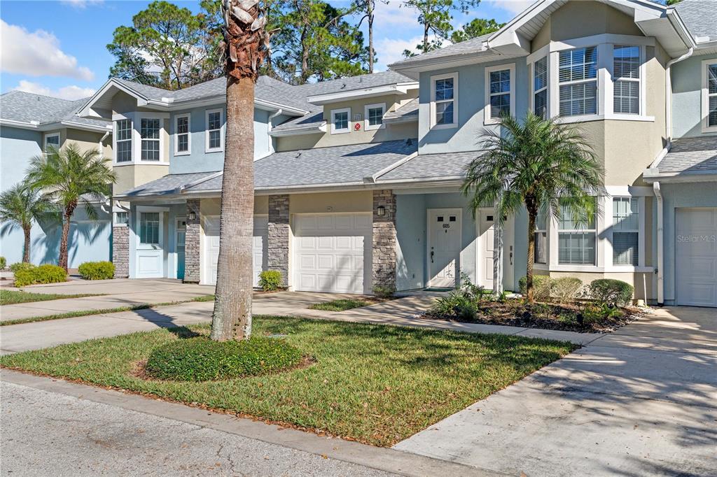 A multi-story townhouse complex with light blue siding, stone accents, and attached garages — 215 BAYBERRY CIRCLE UNIT 605, ST AUGUSTINE, FL