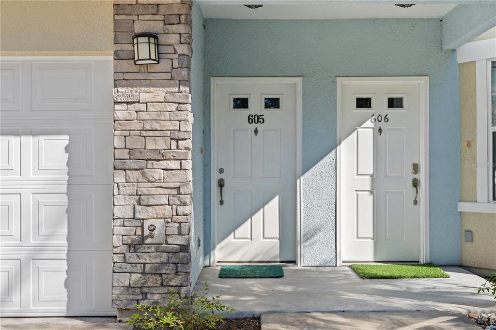 Two white front doors with house numbers 605 and 606 sit on a concrete porch — 215 BAYBERRY CIRCLE UNIT 605, ST AUGUSTINE, FL