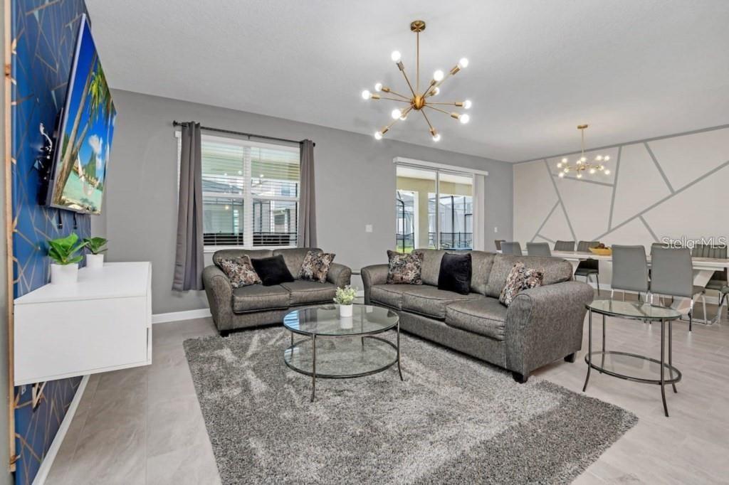 A living room features gray sofas, a glass coffee table, and a blue accent wall — 2846 BOOKMARK DRIVE, KISSIMMEE, FL