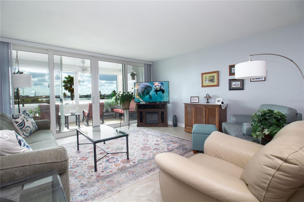 A living room features a patterned area rug, a television, and a balcony with water views — 17920 GULF BOULEVARD UNIT 301, REDINGTON SHORES, FL