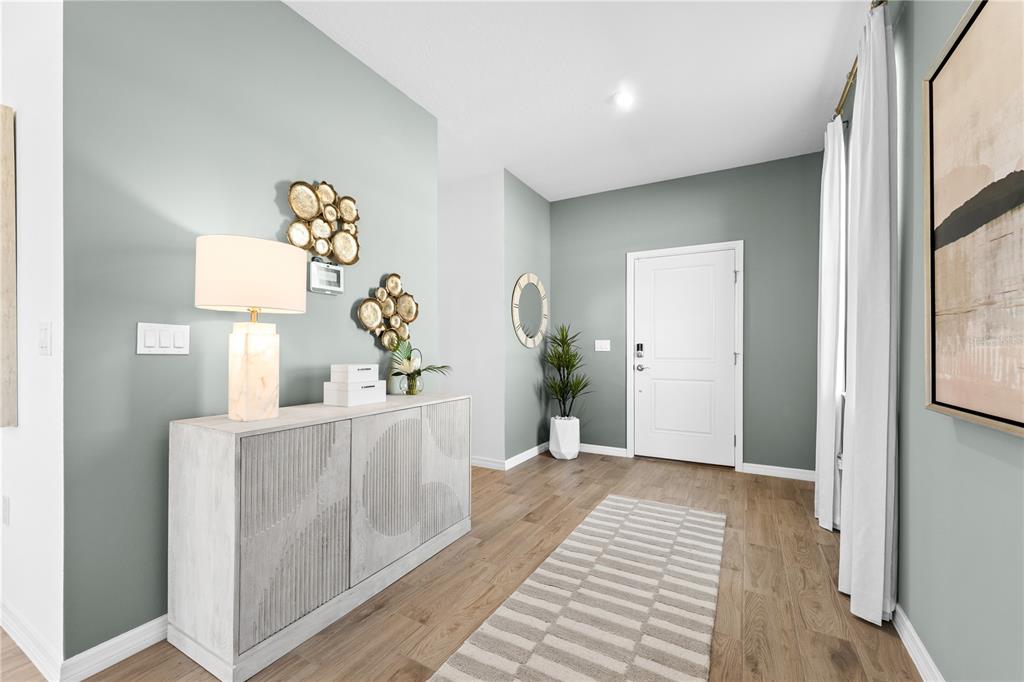 A modern entryway features a light wood console table, a striped rug, and sage-colored walls — 4421 RIVER BEACON BOULEVARD, DAVENPORT, FL