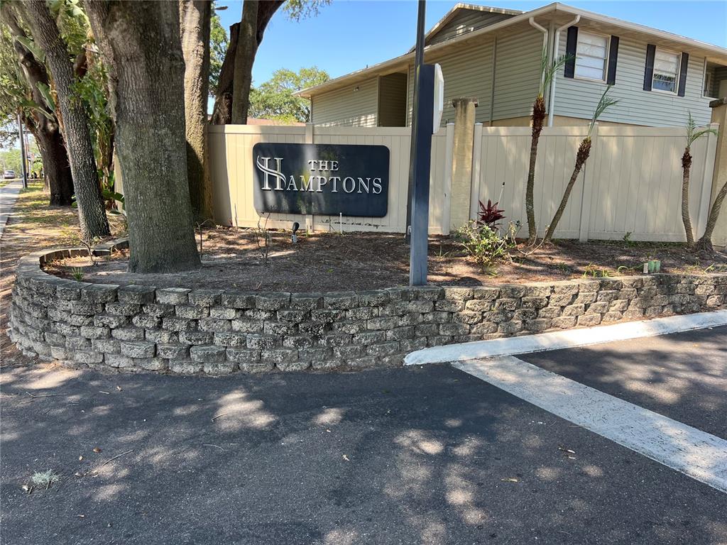 A stone retaining wall sits in front of a sign for The Hamptons apartment complex — 208 RED CEDAR PLACE UNIT 208, BRANDON, FL
